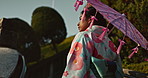 Asian, woman at temple and parasol, walk on bridge with sunshine, tradition and religion with nature. Traditional clothes, culture and wellness, Japanese with travel and umbrella for sun outdoor