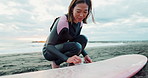 Woman, surfboard wax and happy at beach, thinking and ready for workout, training or wellness in morning. Person, surfer and preparation by ocean, waves and nature with smile for water sport in Japan