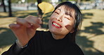 Asian, woman in park and leaf with face and happiness outdoor, explore nature for wellness and environment. Sunshine, plants and portrait, travel and adventure in public garden with smile on journey