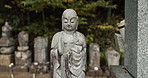 Stone statue in traditional Japanese graveyard with peace, calm and quiet garden with memorial tombstone. Buddha sculpture in outdoor temple cemetery with zen, Asian culture and spiritual history.