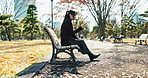 Asian woman, walking and relax on park bench with phone for social media, communication or networking. Female person sitting with mobile smartphone for online search, streaming or break in nature