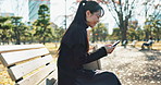 Happy asian woman, phone and typing on park bench for social media, communication or networking. Female person smile in relax on mobile smartphone for online search, streaming or reading in nature