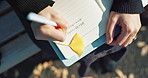 Person, hands and writing in book on park bench for reminder, agenda or memory in nature above. Top view and closeup of writer or journalist taking notes in diary or notebook with pen for planning