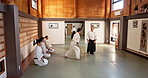 Black belt students, karate or master teaching martial arts in dojo for aikido, movement or self defense. Combat demonstration, Japanese people or training workout for fighting, education or class