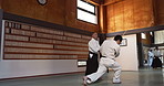 Aikido dojo with sensei, wooden sword and student training for fitness, fight and action in gym. Teaching, learning and men in traditional Japanese martial arts class with aikidoka, bokken and battle