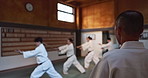 Aikido students, stick or learning martial arts in dojo for practice, body movement or self defense. Combat demonstration, sensei or Japanese people training workout for fighting, education or class