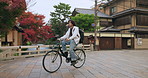 Cycling, travel and man riding by buildings for exercise or transportation to college academy. Fitness, backpack and young male student driving a bicycle to university for carbon footprint by houses.