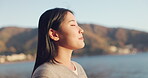 Japanese woman, breathing and peace outdoor, lake or ocean with travel, holiday and mindfulness in nature. Wellness, adventure and care free at beach in Japan, calm with freedom and positivity