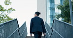 Stairs, walking and back of businessman in the city by office building for travel with career. Outdoor, energy and professional male person commuting on steps to modern workplace in urban town.