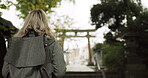 Woman, forest and torii gate in Kyoto with backpack, tourist and back with traditional history. Architecture, japanese culture and shinto shrine in woods with sculpture, memorial and monument