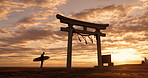 Torii gate, sunset and man with surfboard, ocean and travel adventure in Japan with orange sky. Shinto architecture, Asian culture and calm beach in Japanese nature with person at spiritual monument.