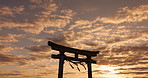 Torii gate, sunset sky in Japan with nature, zen and spiritual history on travel adventure. Shinto architecture, Asian culture and calm clouds on Japanese landscape with sacred monument at shrine.