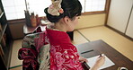 Asian, woman and writing with paper and ink, script or letter with document and creativity, calligraphy and traditional text. Japanese font, writer with black paint at desk for art and tools