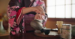 Traditional, teapot and hands of Asian woman with tea for culture with herbs, leaves and flavor in home. Ritual, ceremony and person with herbal beverage for relaxing, calm and wellness for drinking