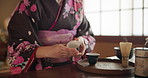 Culture, teapot and hands of Asian woman with tea with traditional herbs, leaves and flavor in home. Kimono, ritual and person with herbal beverage for relaxing, calm and wellness for drinking