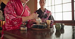 Japanese women, together and traditional tea for friends, respect and kindness to relax with chat at table. Girl, people and prepare for drink, matcha or indigenous clothes with cup, culture and home