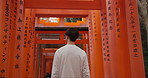 Travel, location and Japanese spiritual shrine in Kyoto with man walking on trail for religion, god and mountain. Fushimi Inari Taisha, monument and back of person experience Torii gates on adventure