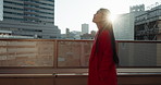 Japanese, woman and travel in city with sun, walking outdoor with buildings and fresh air. Urban view, lens flare on journey and adventure with traveller, smile in cityscape and exploring on trip