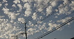 Electricity, power lines and clouds in blue sky for industrial energy, engineering and antenna from below. Silhouette, background and electrical pylon pole outdoor for infrastructure, wires and cable