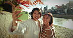 Selfie, smile and Asian women at river for holiday travel, fun and happy adventure together with nature. Digitsal photography, peace sign and couple of friends relax on outdoor vacation in Japan.
