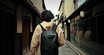 Person, walk and Japanese street on holiday for explore city, international travel or learning culture. Traveler, back view and stroll or discover architecture buildings, outdoor journey or adventure