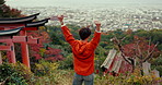Man, celebration and mountain with landscape, view and city by Fushimi Inari shrine for shinto religion. Japanese person, hiking and cheers with fist by trees, pillar and spiritual journey in Kyoto