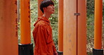 Fushimi Inari shrine, man and shinto religion with thinking, ideas and walk in nature for connection to god. Japanese person, outdoor and trees with pillar, spiritual journey and vision in Kyoto