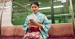 Japan woman, travel and train on smartphone, typing and metro transport on vacation on social media. Person, cellphone and traditional clothes on trip with technology and commute in town in kimono