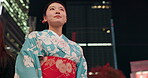 Woman, happy and night in city with kimono, travel and leisure in heritage celebration in positive attitude. Person, smile or traditional clothes by urban town buildings or journey in tokyo culture