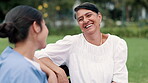 Senior, nature or nurse on bench with a happy woman in a park garden for wellness or laughing. Relax, talking or funny caregiver with smile, joy or patient for outdoor rehabilitation, love or nursing