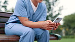 Nurse, typing and cellphone on bench in park, outdoor and internet connection for networking in city. Healthcare employee, hands or mobile phone for message or email, digital or app in nature in town