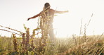 Nature, freedom and back of woman in a field embracing the sunset with plants, grass and greenery. Energy, moving and female person with leaves for calm or peaceful environment in countryside.