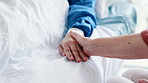 Patient, person and holding hands on hospital bed for comfort for health problem for medical support, love or empathy. People, fingers and embrace at clinic for diagnosis compassion, pain or virus