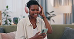 African woman, headphones and phone on sofa, relax and happy for streaming subscription in lounge. Girl, person and excited for audio tech, sound or reading with smile in living room on social media