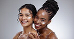 Women, cream and beauty with diversity in studio with facial treatment, happiness or glowing skin. Friends, model and portrait with smile for cosmetics, dermatology or body care on gray background
