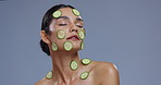 Skincare, cucumber and face of woman on blue background for wellness, beauty and cosmetics. Dermatology, spa benefits and person with vegetable for nutrition, organic and natural products in studio