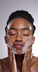 Black woman, face cream and wash for skincare, hygiene or grooming on a gray studio background. Closeup of African female person cleaning creme, lotion or facial treatment for cleanse or rejuvenation