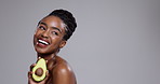 Beauty, avocado and woman laugh in studio for healthy cosmetics, nutrition or detox on grey background. Happy african model thinking of fruits for sustainable benefits, eco skincare or diet at mockup