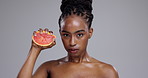 Skincare, squeeze grapefruit and face of black woman on gray background for wellness, beauty and cosmetics. Dermatology, portrait and person for nutrition, organic fruit or natural benefits in studio