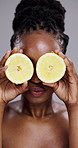 Happy black woman, lemon and skincare in vitamin C, beauty or detox on a gray studio background. Portrait of African female person, face or model smile with natural organic citrus fruit for treatment