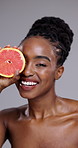 Grapefruit, beauty and face of happy woman in studio for vitamin c, benefits or vegan diet on grey background. Portrait, african model or citrus fruits for eco skincare, sustainable cosmetics or glow