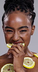 Black woman, skincare and eating lemon for vitamin C, beauty or detox on a gray studio background. Portrait of African female person, face or model biting natural organic citrus fruit for nutrition