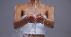 Water, skincare and hands of woman on gray background for cleaning, spa wellness and cosmetics. Dermatology, beauty and person with splash for washing, facial treatment and healthy skin in studio