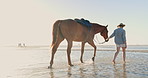Woman, horse and walk at beach, water and adventure for training, development and health on vacation in summer. Cowgirl, equine animal and pet with journey, travel or holiday by ocean, sea and back