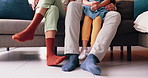 Legs of mom, dad and kid on sofa with smile, love and bonding together in living room of home. Feet of family with father, mother and daughter sitting on couch, relax and sitting in apartment lounge.