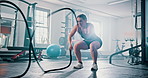 Gym, fitness and woman with battle rope wave for muscle growth, strength development and power exercise. Fast action, endurance and athlete resilience in intense workout, challenge and hard work