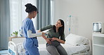 Doctor, patient and woman in a consultation, pain and conversation with nurse and healthcare. Professional, appointment and medical with discussion and treatment with diagnosis and injury in hospital