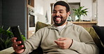 Home, funny and man on a couch, cellphone or typing with social media or connection in a lounge. Apartment, person on a sofa or meme with smartphone or communication with  digital app and laughing