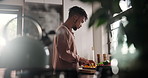 Food, cooking and man in kitchen of home, cutting organic fruit for health, diet or nutrition. Nutritionist, wellness and detox with young person in apartment for preparation of green meal or snack