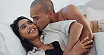 Happy couple, relax and kissing on bed for love, morning romance or embrace in trust or care at home. Young man and woman smile lying in bedroom hug for intimacy, passion or bonding together at house